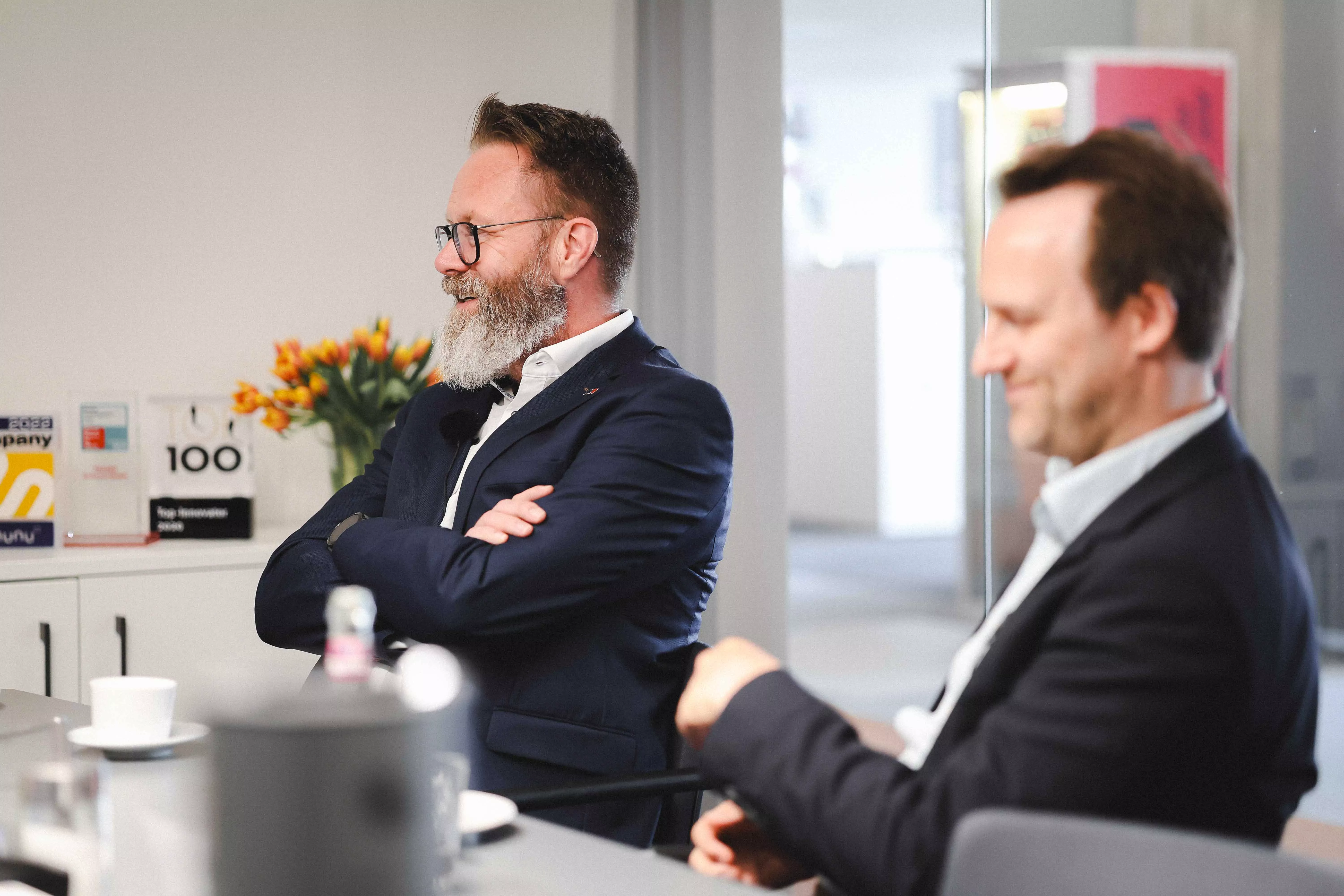 Im Vordergrund: Dr. Johannes Ripken im Profil; im Hintergrund lächelnd Claus Ruhe Madsen. | In the foreground: Dr. Johannes Ripken in profile; in the background, Claus Ruhe Madsen smiling.